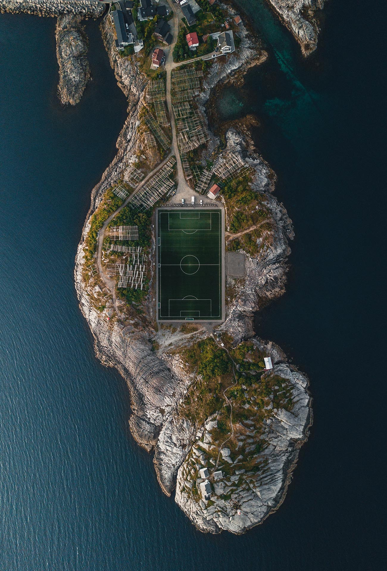 Luftbild auf einen Fußballplatz, umgeben von Meer.